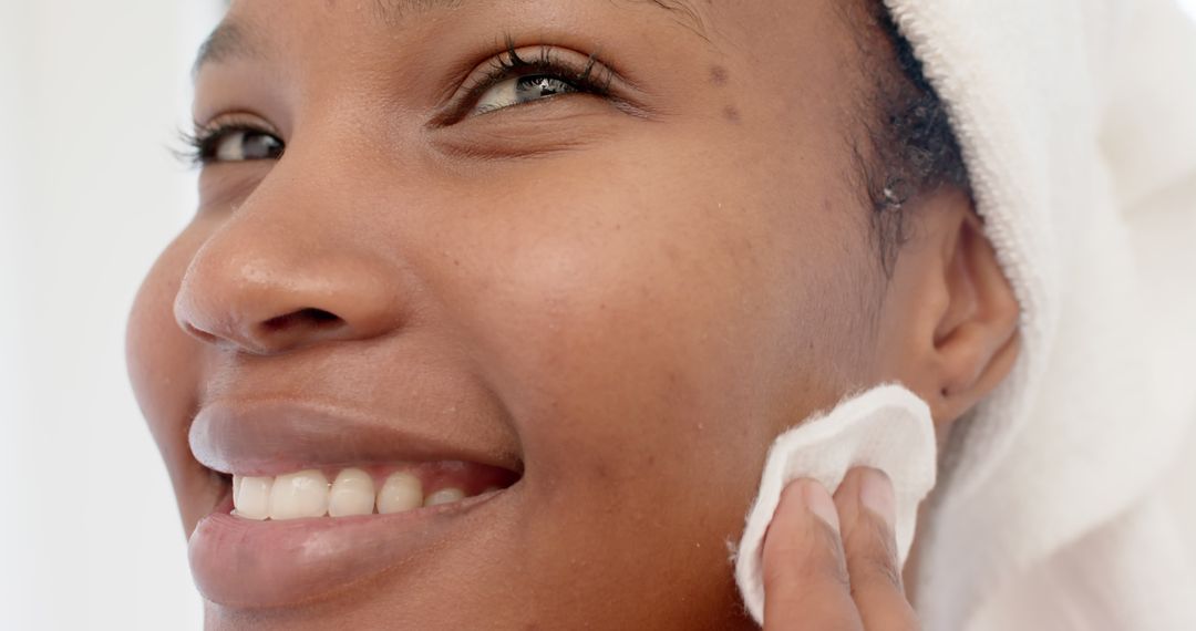 Smiling woman cleansing face with cotton pad - Free Images, Stock Photos and Pictures on Pikwizard.com