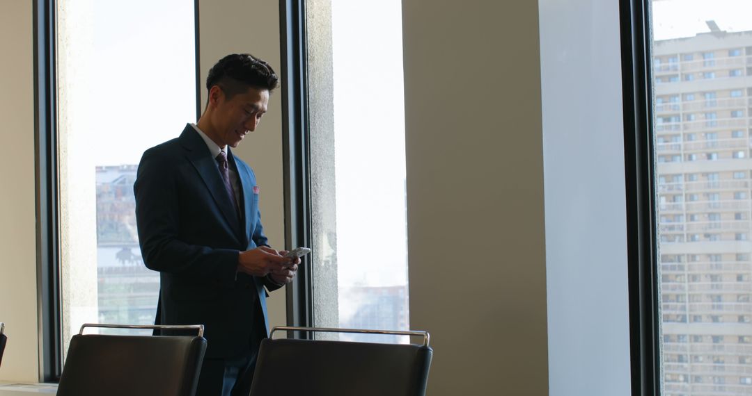 Businessman Using Smartphone in Modern Office with City View - Free Images, Stock Photos and Pictures on Pikwizard.com