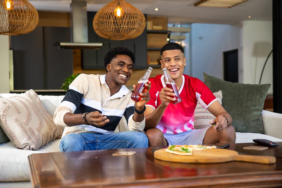 Diverse Friends Enjoying Together on Sofa with Refreshments and Snacks
