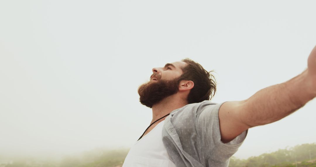 Carefree Bearded Man Enjoying Beach Breeze with Open Arms