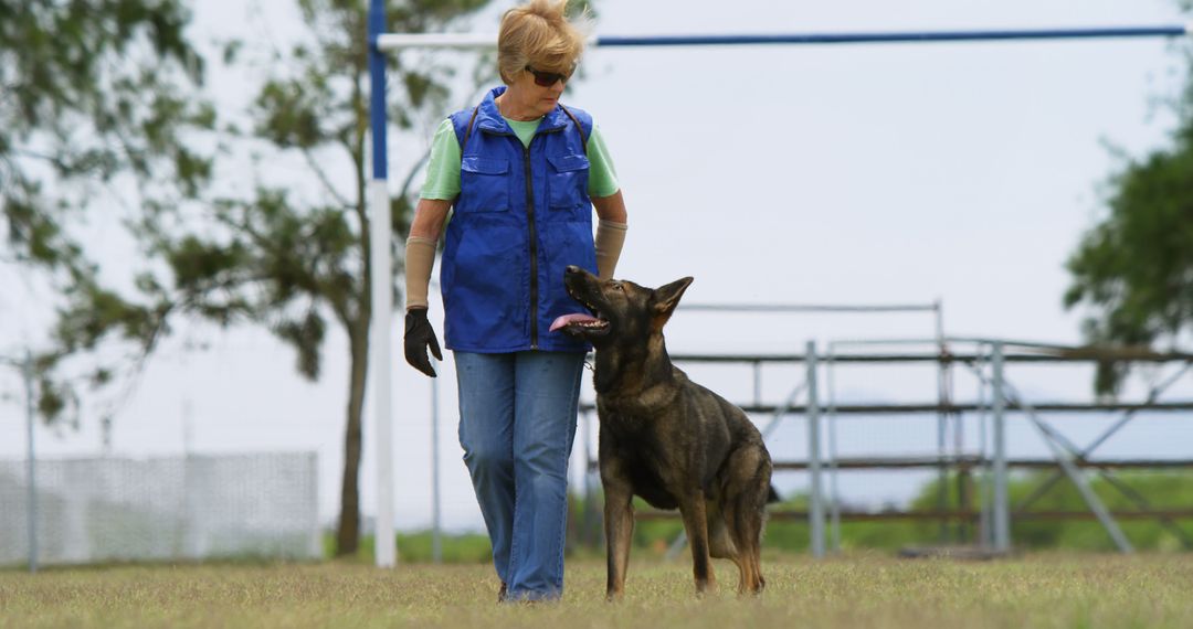 Elderly Woman Walking German Shepherd on Outdoor Field - Free Images, Stock Photos and Pictures on Pikwizard.com