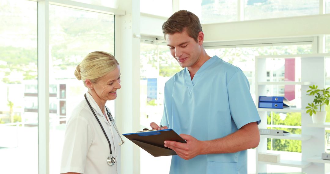 Smiling Medical Professionals Discussing Patient Notes in Bright Office - Free Images, Stock Photos and Pictures on Pikwizard.com