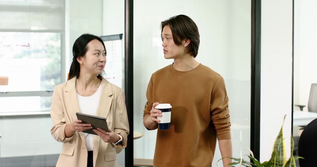 Colleagues Engaging in Conversation with Tablet and Coffee in Modern Office