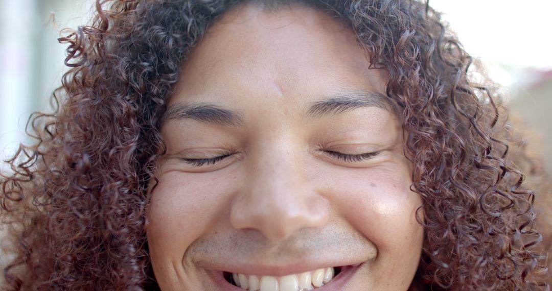 Close-Up Face of Person with Curly Hair Smiling with Eyes Closed - Free Images, Stock Photos and Pictures on Pikwizard.com