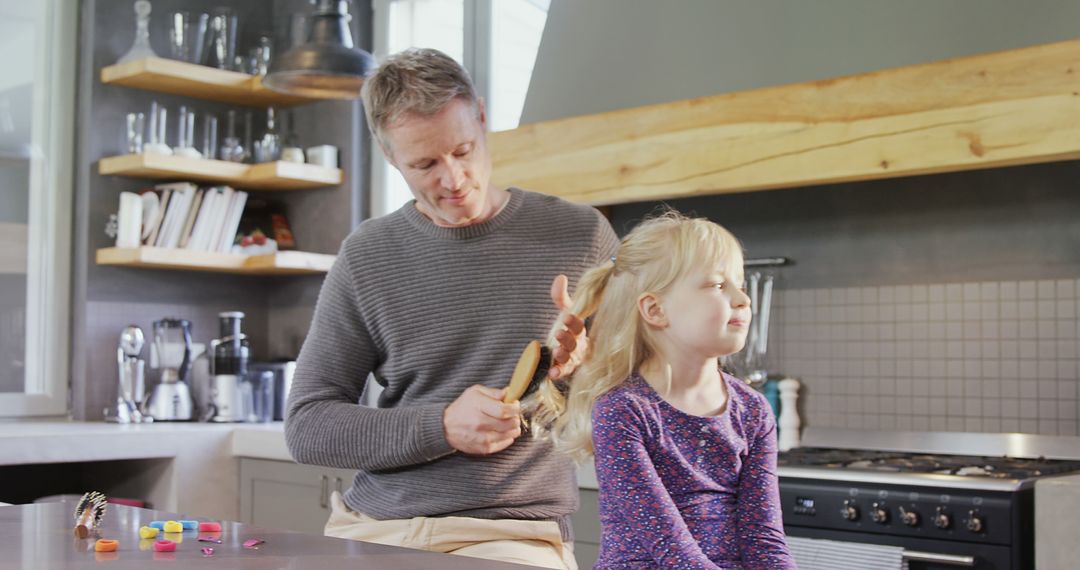 A father tenderly brushes his daughter's hair in a cozy kitchen, implying a close relationship. - Free Images, Stock Photos and Pictures on Pikwizard.com