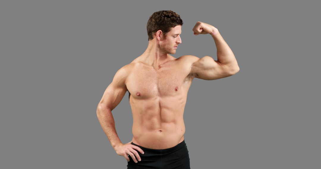 A young Caucasian man showcases his muscular physique by flexing his bicep, with copy space - Free Images, Stock Photos and Pictures on Pikwizard.com