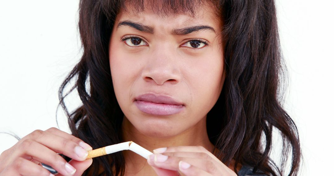 An African American young woman appears skeptical as she breaks a cigarette, with copy space - Free Images, Stock Photos and Pictures on Pikwizard.com