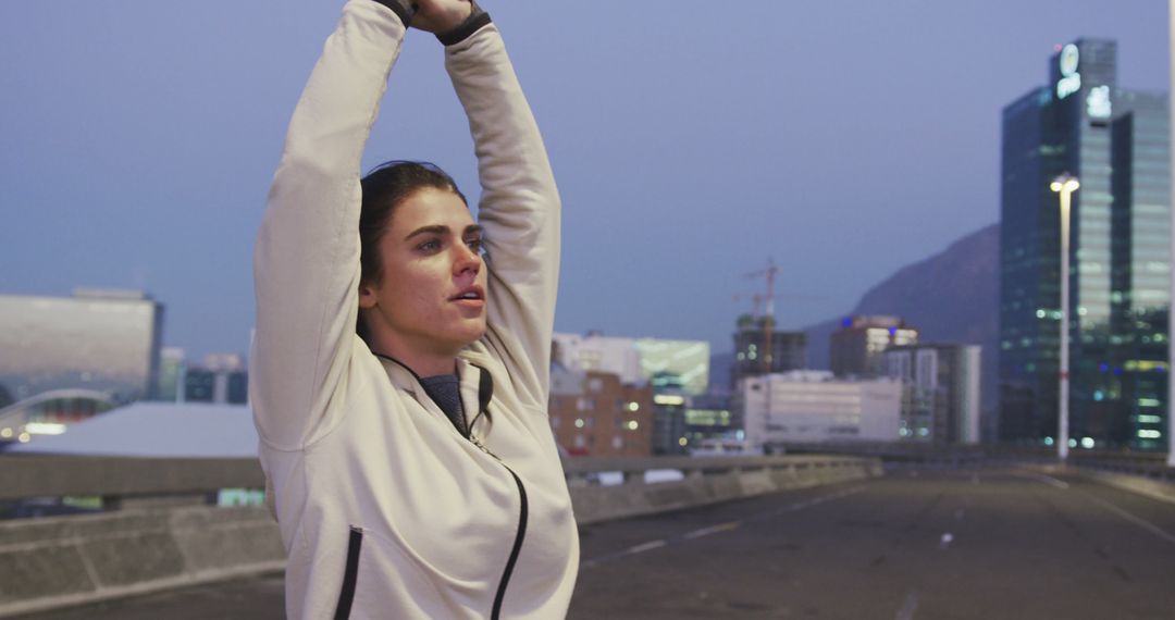 Determined Female Runner Stretching Before City Run at Dusk - Free Images, Stock Photos and Pictures on Pikwizard.com