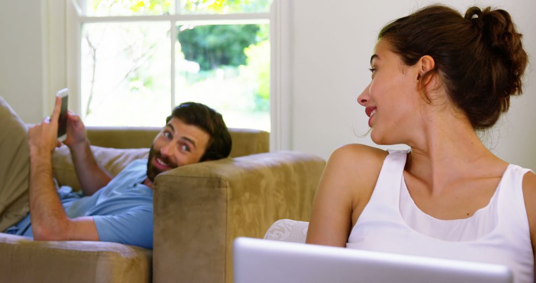 Playful Couple Relaxing with Gadgets at Home