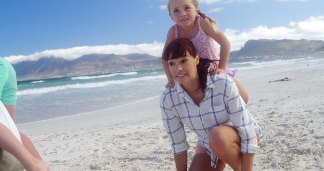 Mother giving daughter piggyback ride on sandy beach - Free Images, Stock Photos and Pictures on Pikwizard.com