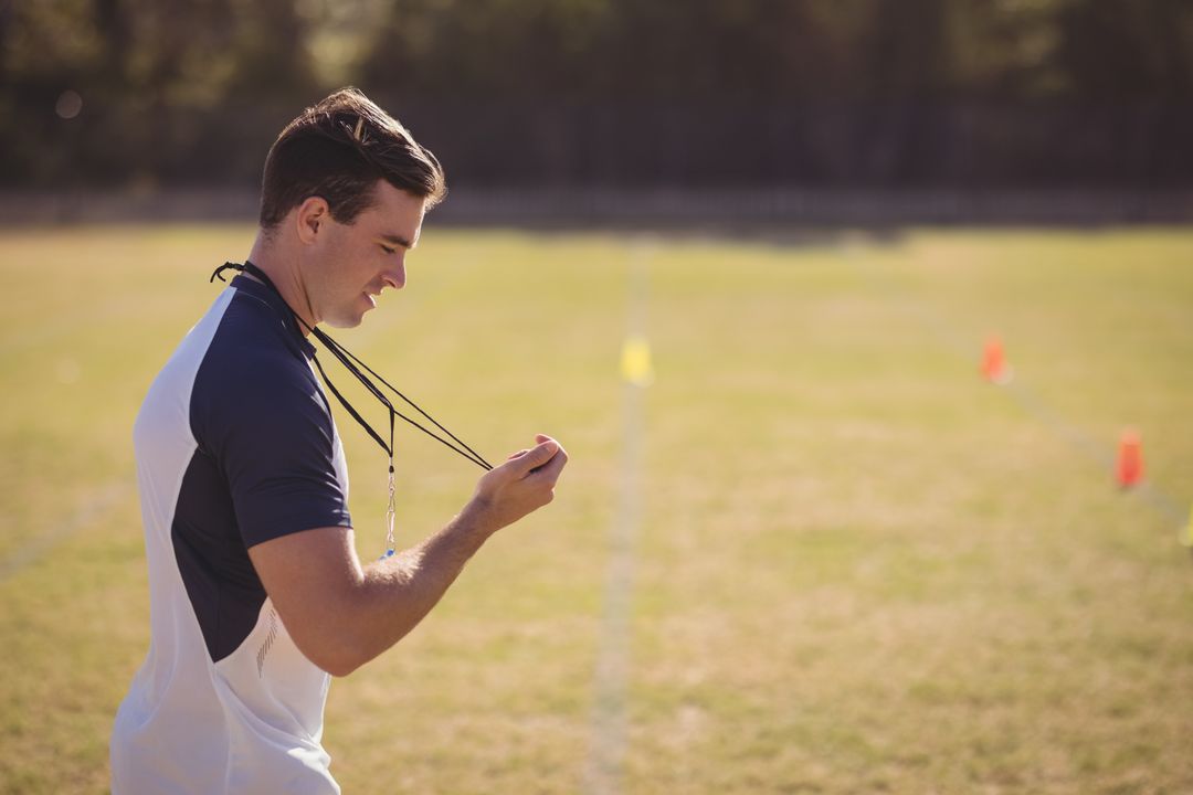 Male Coach Inspiring on Athletic Field with Whistle