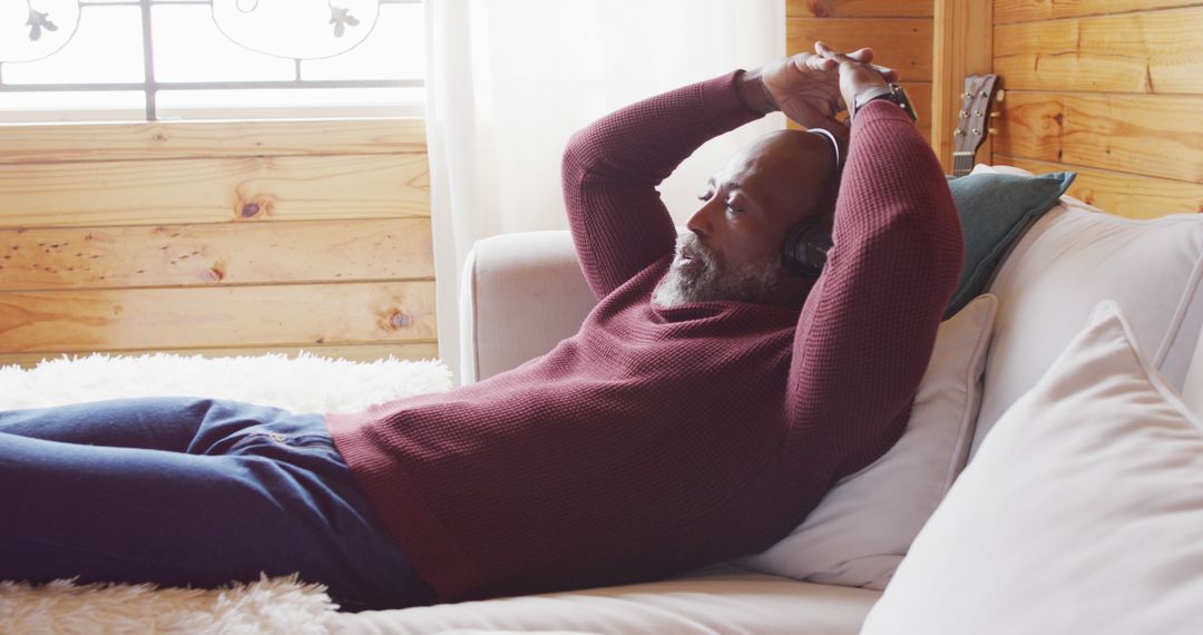 Relaxed Man Listening to Music on Cozy Couch in Wooden Cabin - Free Images, Stock Photos and Pictures on Pikwizard.com