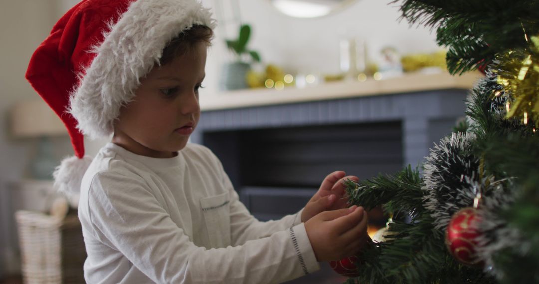 Young Child Decorating Christmas Tree with Santa Hat in Cozy Living Room - Free Images, Stock Photos and Pictures on Pikwizard.com