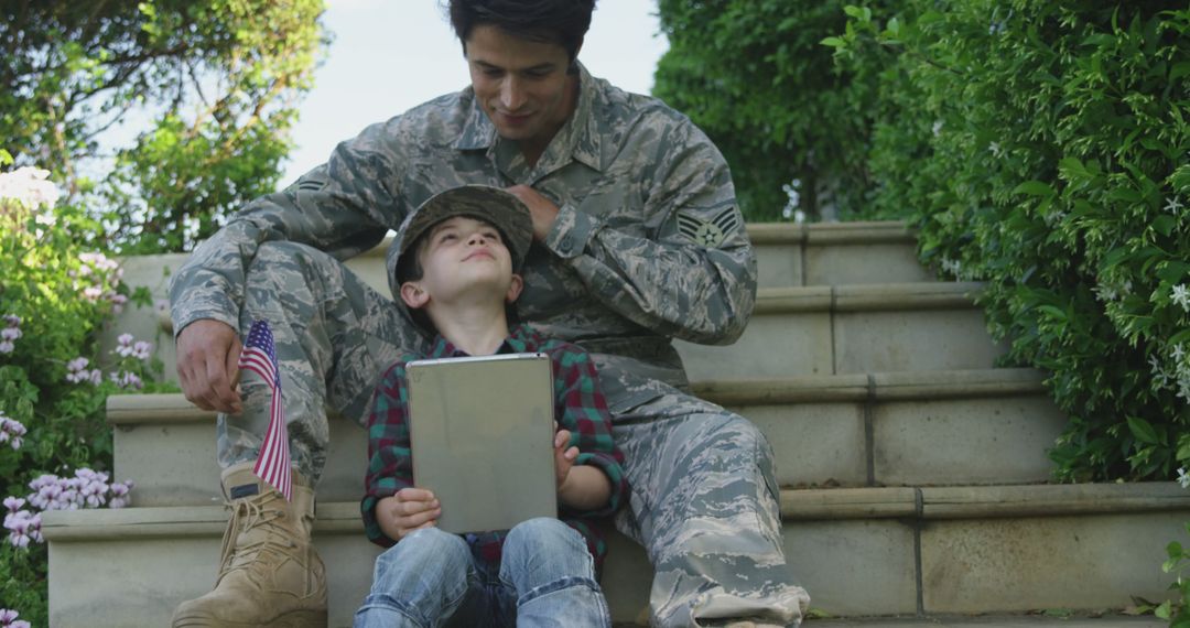 Military Father Smiling with Young Son Holding Tablet on Steps - Free Images, Stock Photos and Pictures on Pikwizard.com