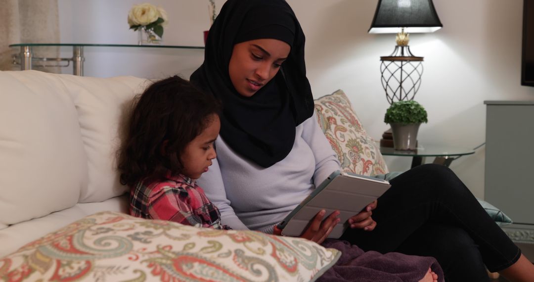 Mother and Daughter in Hijab Using Tablet in Cozy Living Room