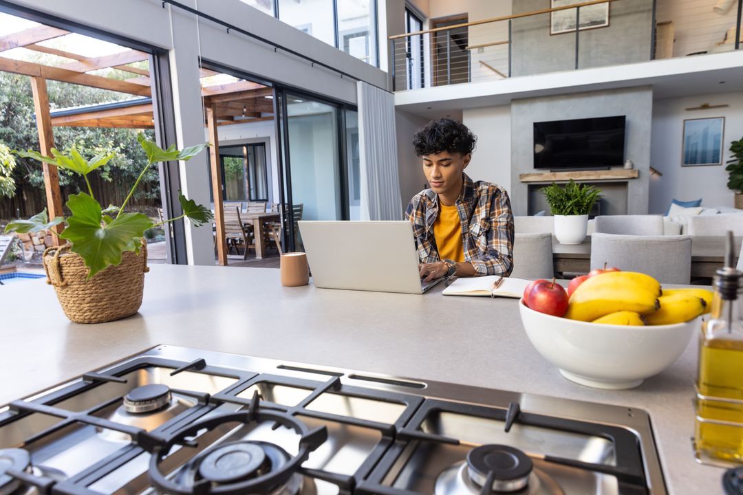 Man Using Laptop at Modern Kitchen Island with Fruit Bowl