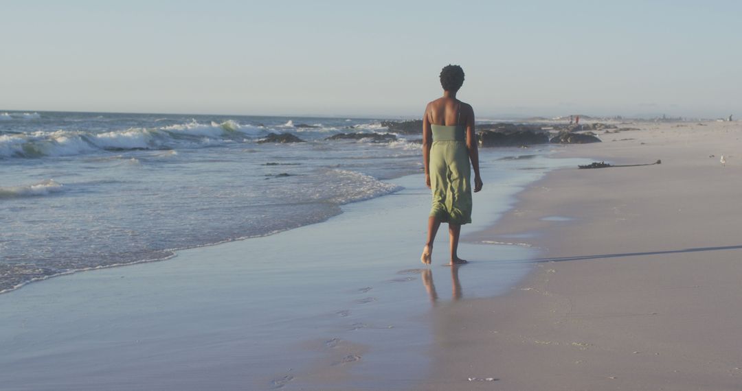 Solitary Woman Walking Along Sandy Beach at Sunset - Free Images, Stock Photos and Pictures on Pikwizard.com