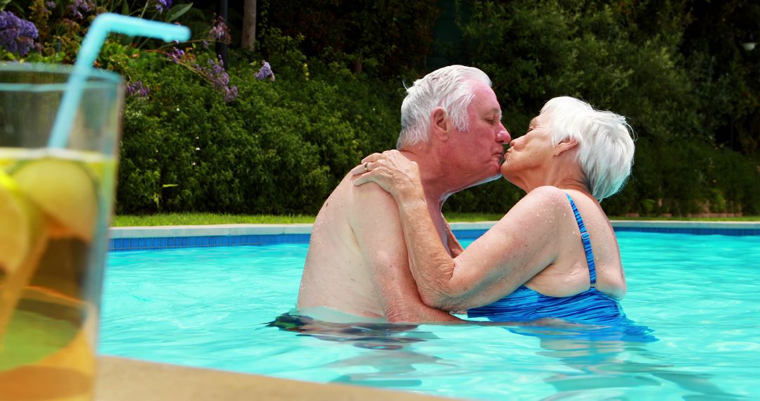 Senior couple kissing each other in the pool on a sunny day - Free Images, Stock Photos and Pictures on Pikwizard.com