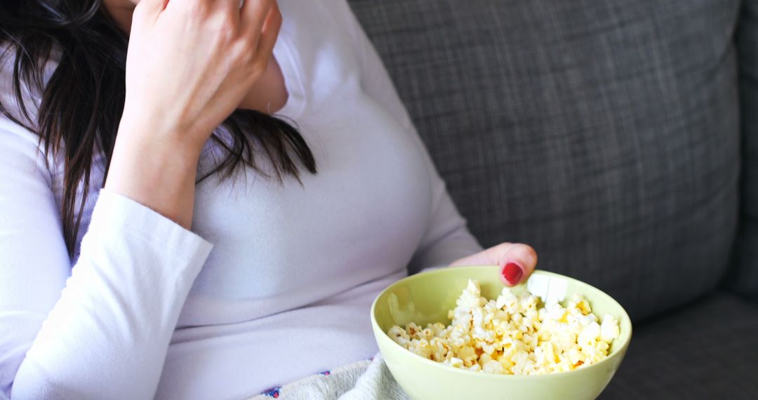 Woman Relaxing on Sofa Enjoying Popcorn - Free Images, Stock Photos and Pictures on Pikwizard.com