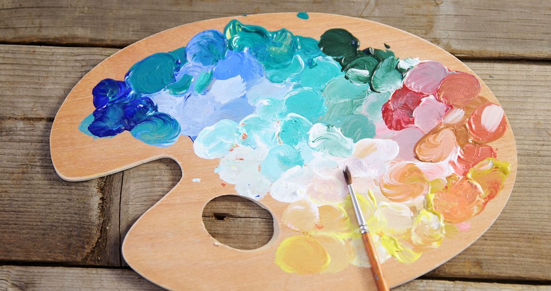 Colorful Artist Palette with Paintbrush on Wooden Table - Free Images, Stock Photos and Pictures on Pikwizard.com