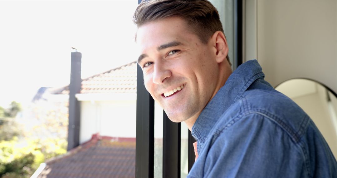 Smiling Man Leaning on Balcony with Scenic Rooftop View