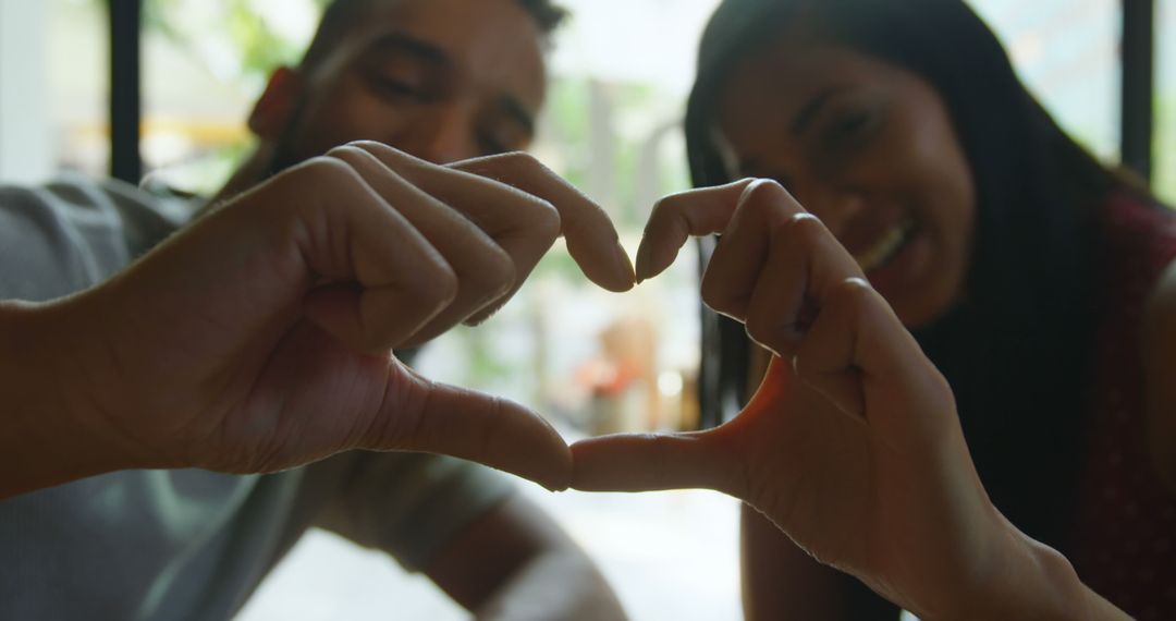 Happy Couple Making Heart Gesture at Cafe