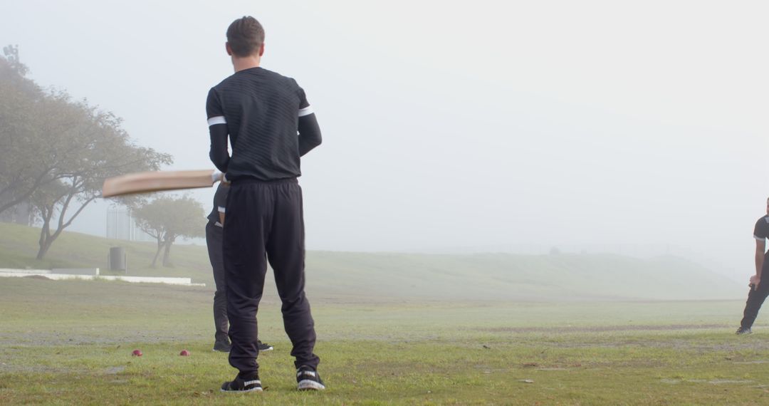 Cricket Practice in Misty Field with Teammates in Black