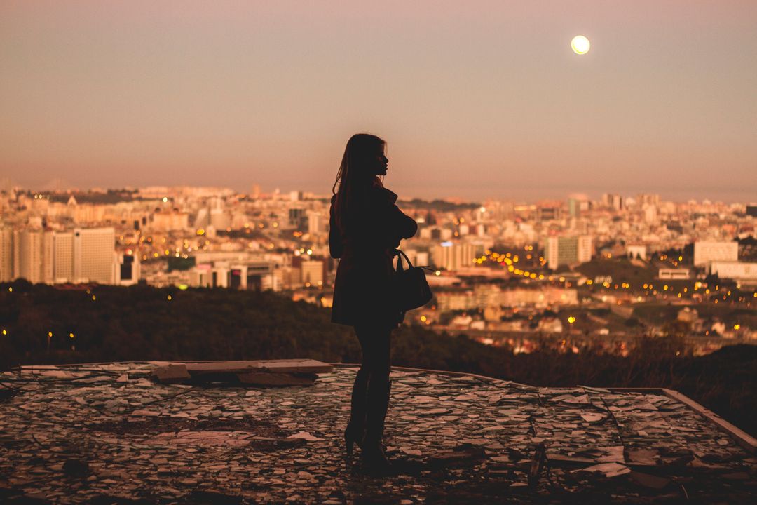 Silhouette of Woman Overlooking City at Sunset with Full Moon - Free Images, Stock Photos and Pictures on Pikwizard.com