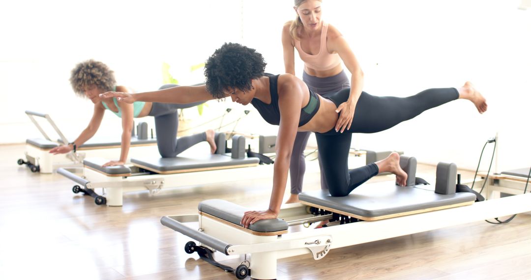 Women Practicing Pilates on Reformer Machines at Modern Fitness Studio
