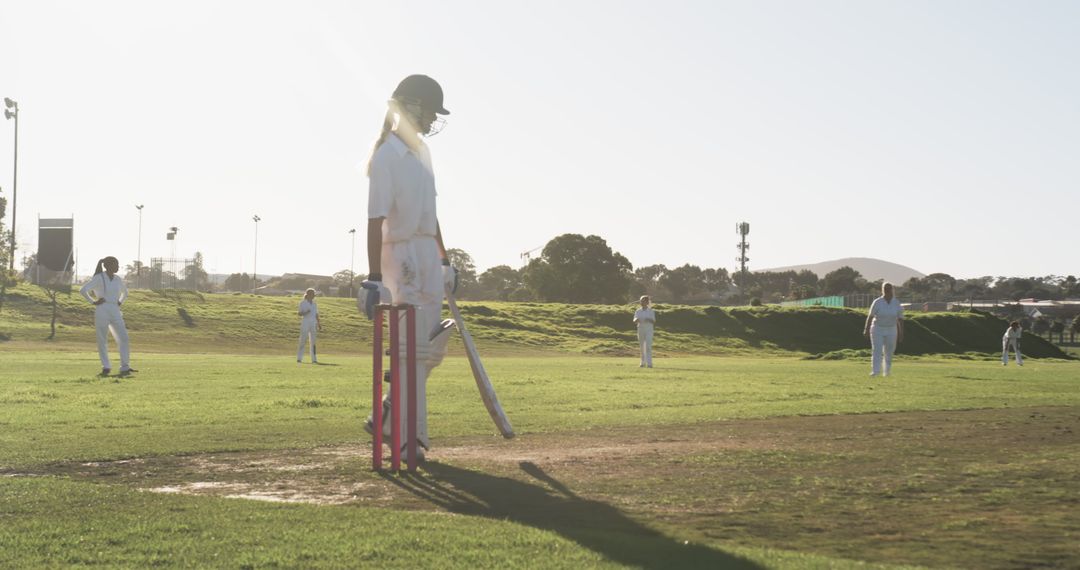 Female Cricket Player Awaiting Ball on Sunlit Playing Field
