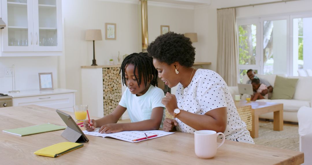 Mother and Son Learning Together at Home Using Tablet and Workbook