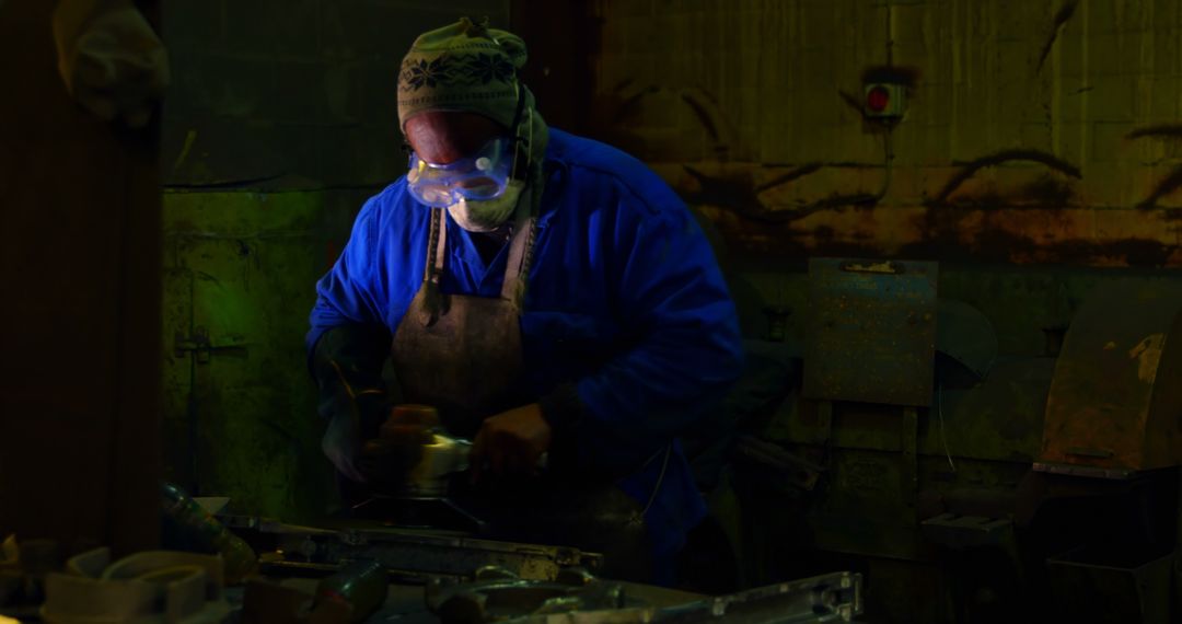 Industrial Worker Grinding Metal in Dim Workshop - Free Images, Stock Photos and Pictures on Pikwizard.com