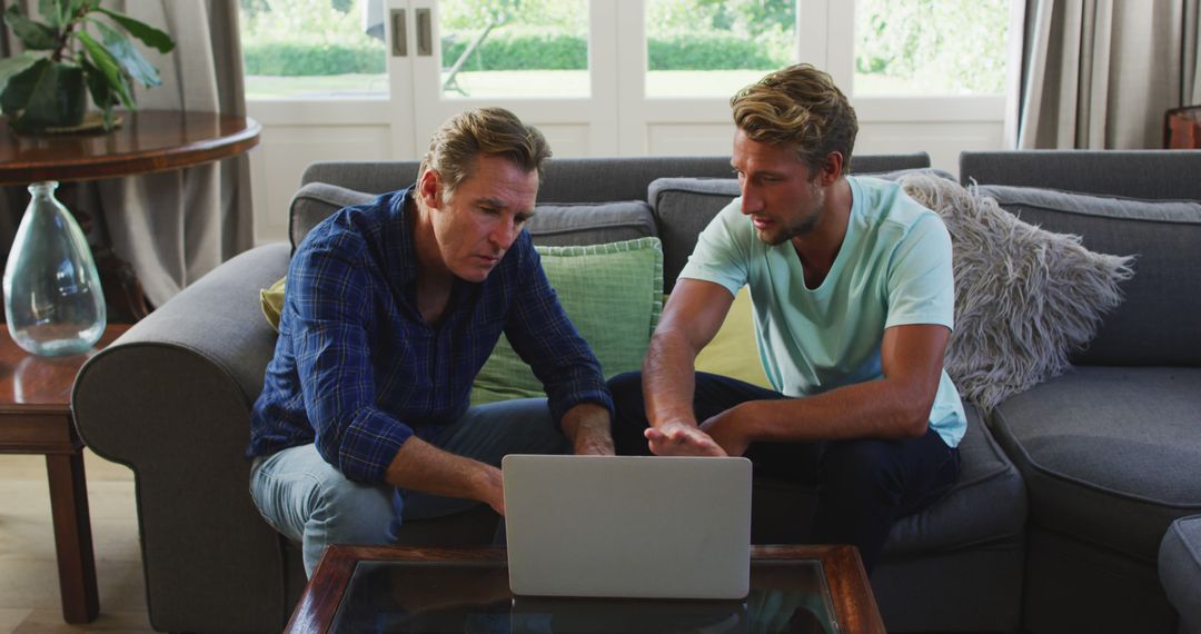 Two Men Discussing Work on Laptop in Modern Living Room - Free Images, Stock Photos and Pictures on Pikwizard.com