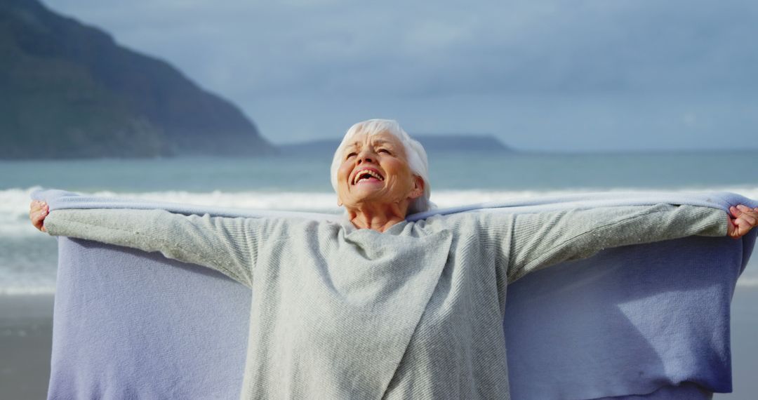 Senior Woman Enjoying Windy Beach with Open Arms - Free Images, Stock Photos and Pictures on Pikwizard.com