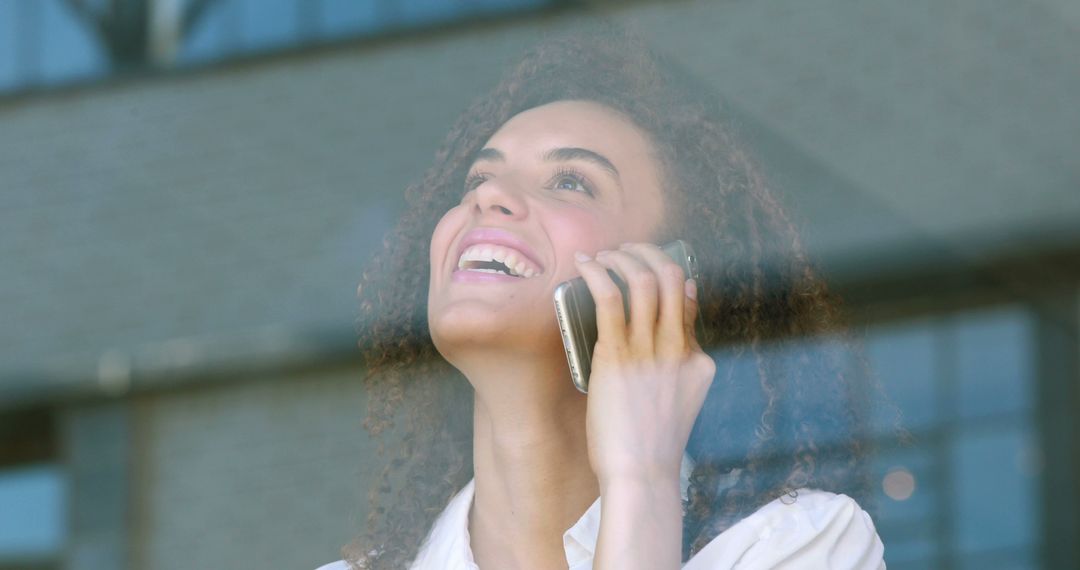 Smiling Young Professional Woman Speaking On Mobile Phone Through Window - Free Images, Stock Photos and Pictures on Pikwizard.com