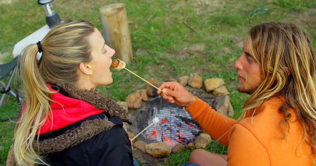 Couple enjoying marshmallows by campfire in outdoor setting - Free Images, Stock Photos and Pictures on Pikwizard.com