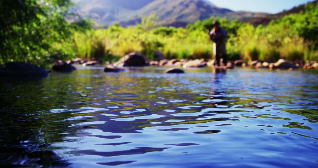 Tranquil Mountain Stream with Angler in Background - Free Images, Stock Photos and Pictures on Pikwizard.com