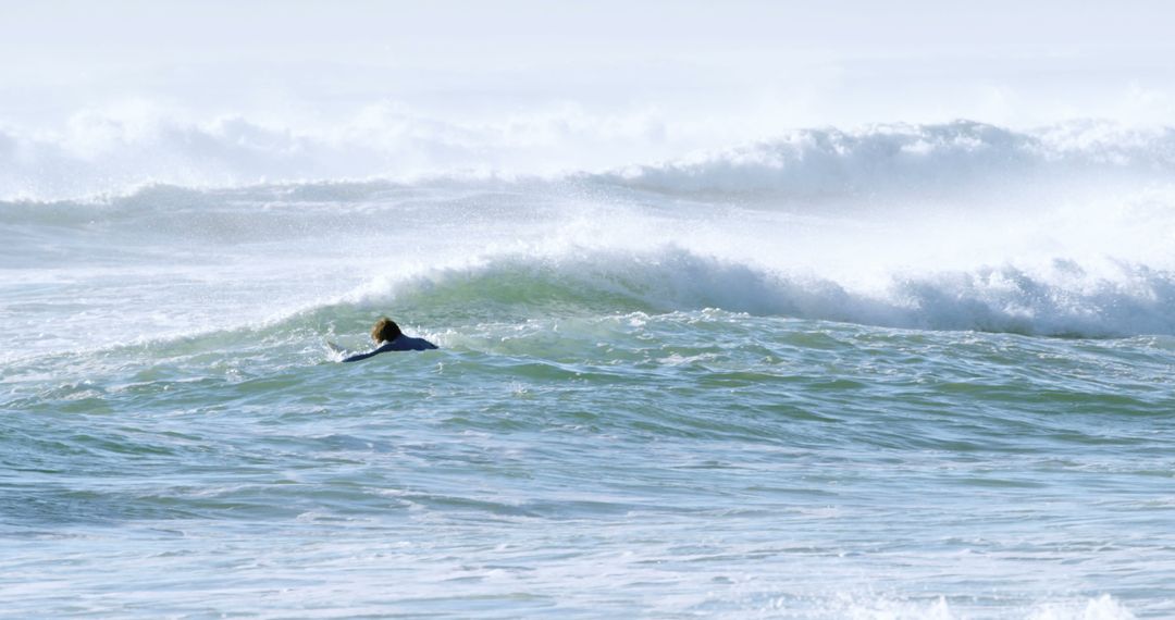 Surfer Paddling Through Ocean Waves on Sunny Day - Free Images, Stock Photos and Pictures on Pikwizard.com