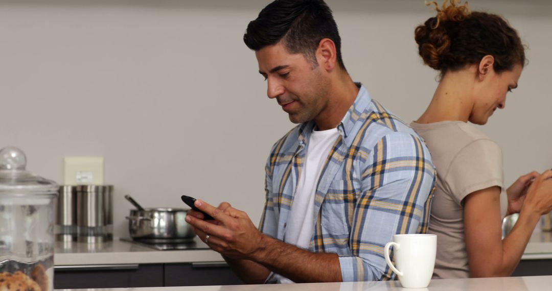 Couple Engaged in Back-to-Back Texting Conversation in Kitchen