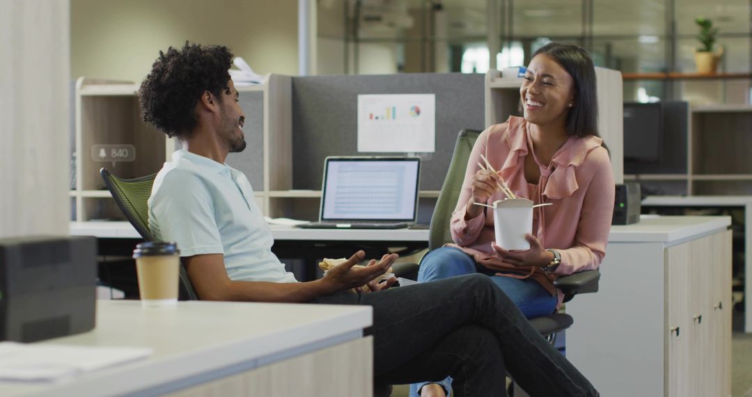 Coworkers Sharing Casual Lunch and Laughing During Break in Modern Open-Plan Workspace