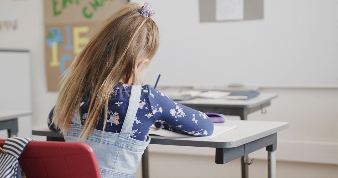 Young Schoolgirl Writing in Notebook During Class