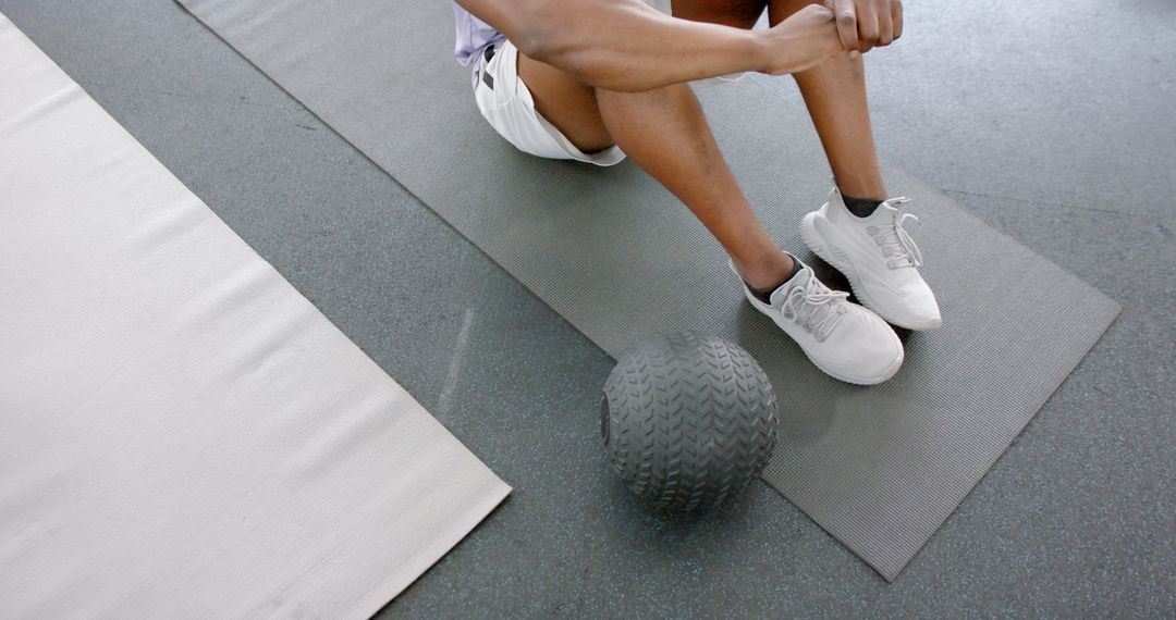 Athlete Takes Rest on Gym Floor with Medicine Ball for Post-Workout Recovery
