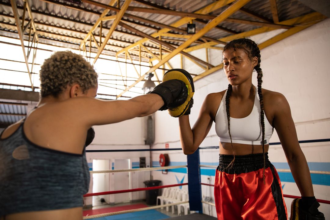 Two biracial women helping each other training in boxing ring - Free Images, Stock Photos and Pictures on Pikwizard.com