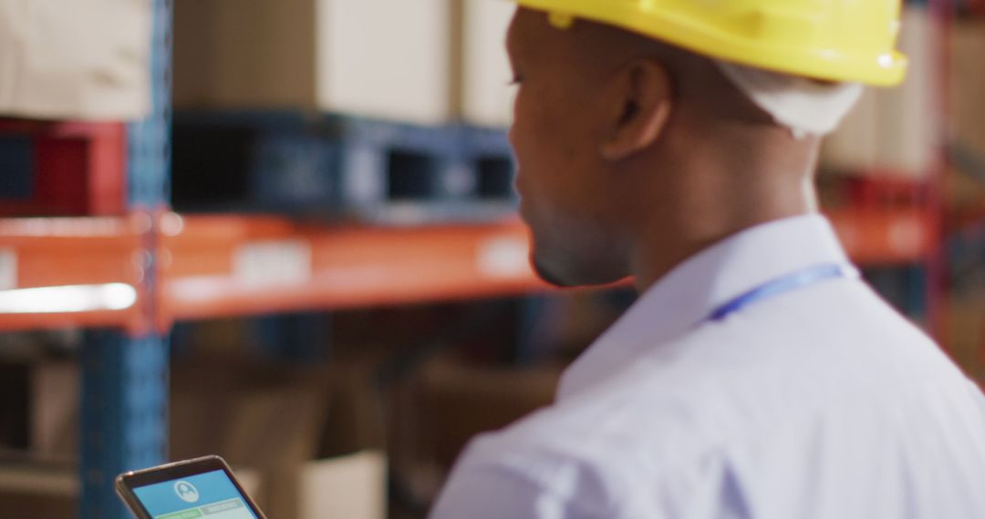 Warehouse Worker in Hard Hat Using Smartphone