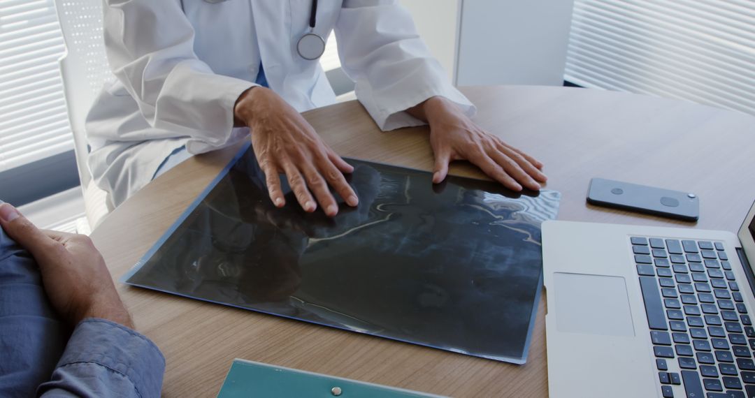 Doctor Examining X-ray Scan with Patient During Consultation - Free Images, Stock Photos and Pictures on Pikwizard.com