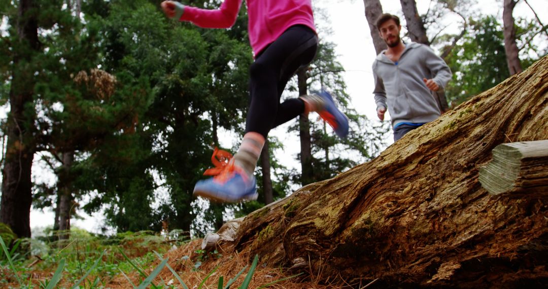 Young Runners Leaping Over Log in Forest Trail Adventure