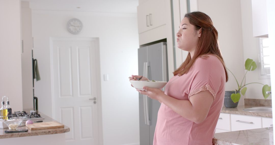 Plus Size Woman Enjoying Fresh Salad in Modern Kitchen