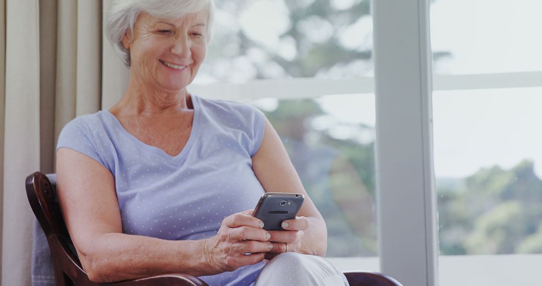 Senior Woman Smiling and Using Smartphone in Bright Room - Free Images, Stock Photos and Pictures on Pikwizard.com