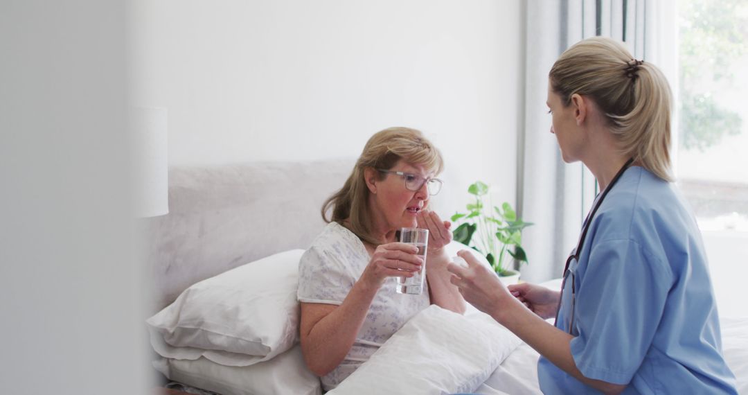 Caucasian senior woman sitting on bed and taking pills from female doctor - Free Images, Stock Photos and Pictures on Pikwizard.com