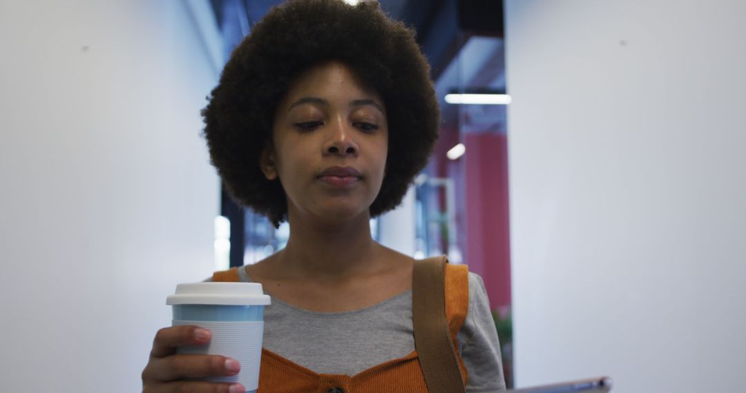 Young Woman Holding Coffee Cup in Office Corridor - Free Images, Stock Photos and Pictures on Pikwizard.com